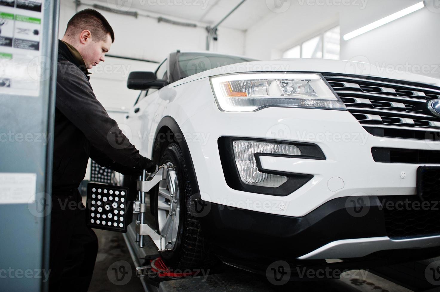 Auto mechanic sets american SUV car for diagnostics and configuration camber check in workshop of service station.. photo