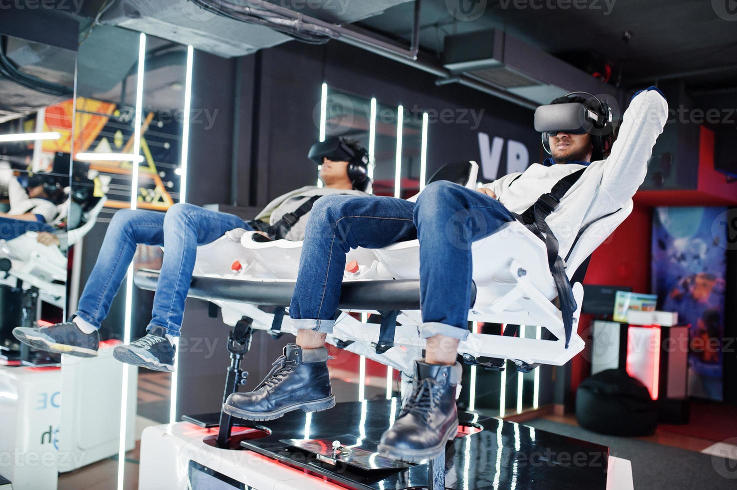Two young indian people having fun with a new technology of a vr headset at virtual reality simulator. photo