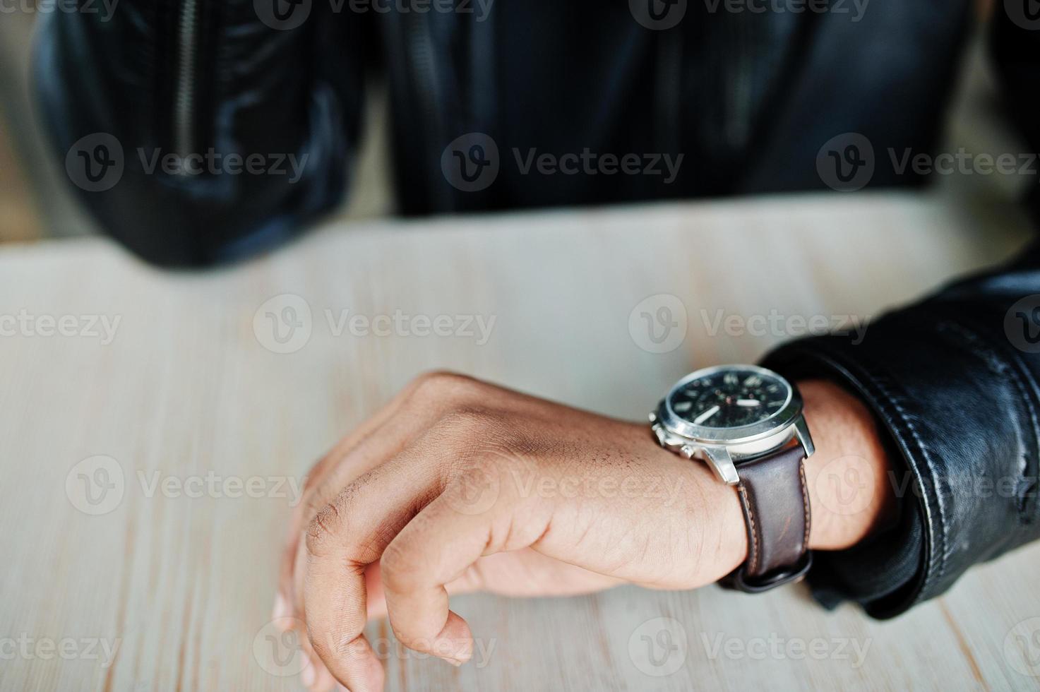 Hand of man wear leather jacket looking at watches. photo