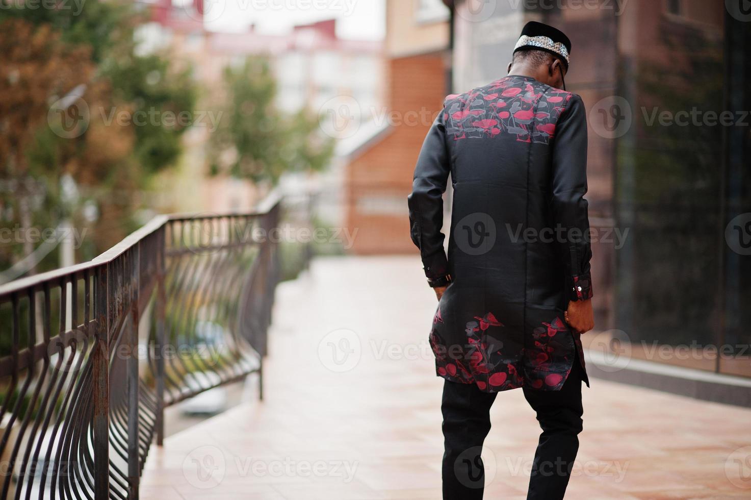 Back of handsome afro american man wearing traditional clothes, cap and eyeglasses in modern city. photo