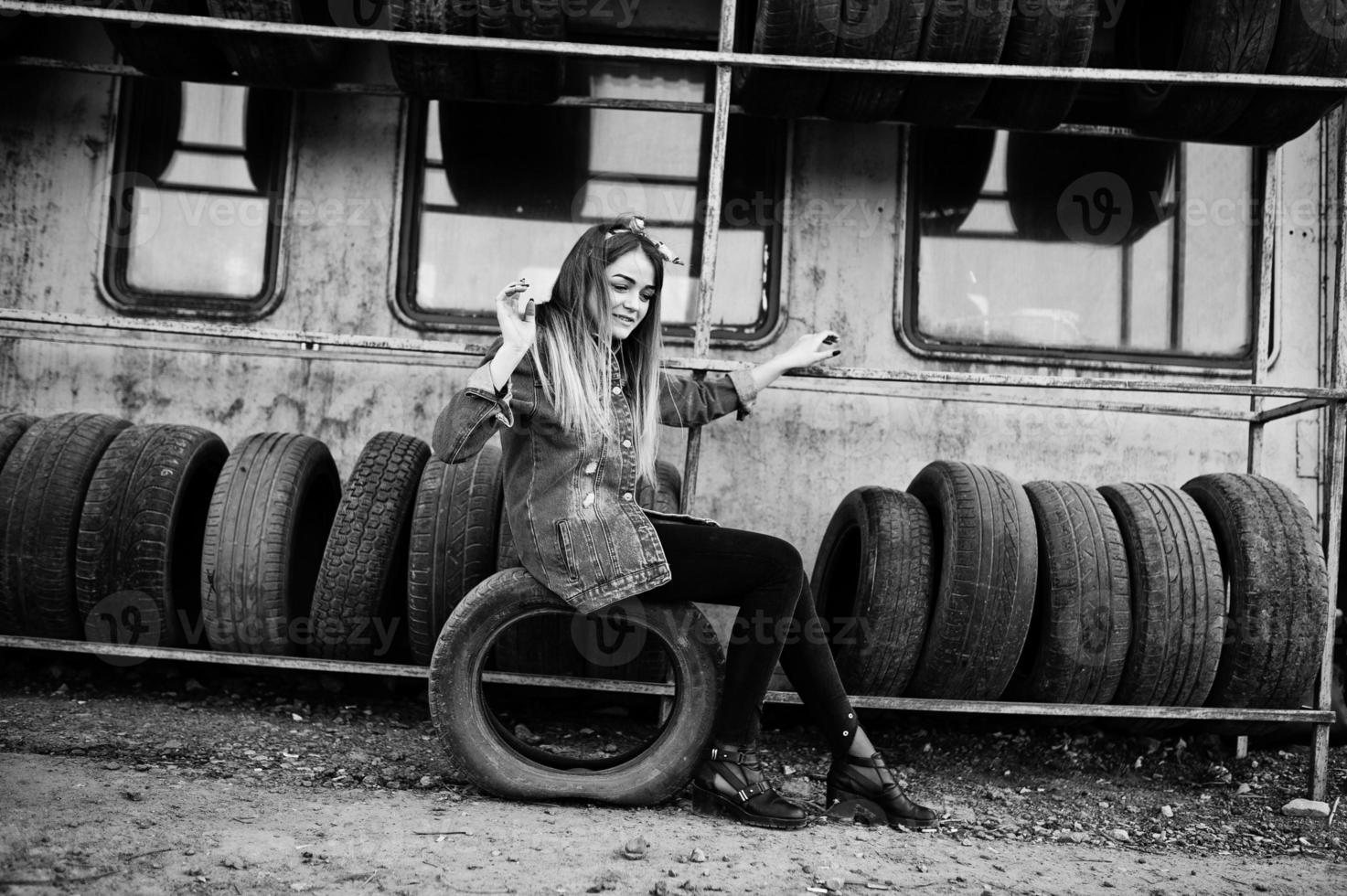 Young hipster girl in jeans jacket and head scarf at tire fitting zone. photo