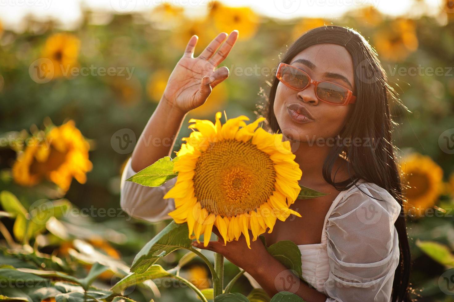 Pretty young black woman wear summer dress pose in a sunflower field. photo