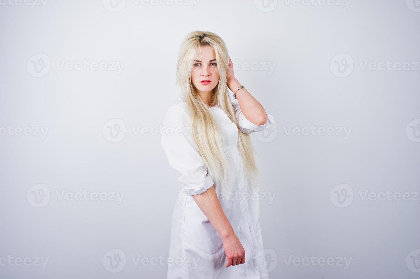 atractiva rubia doctora o enfermera en bata de laboratorio aislada en fondo blanco. foto