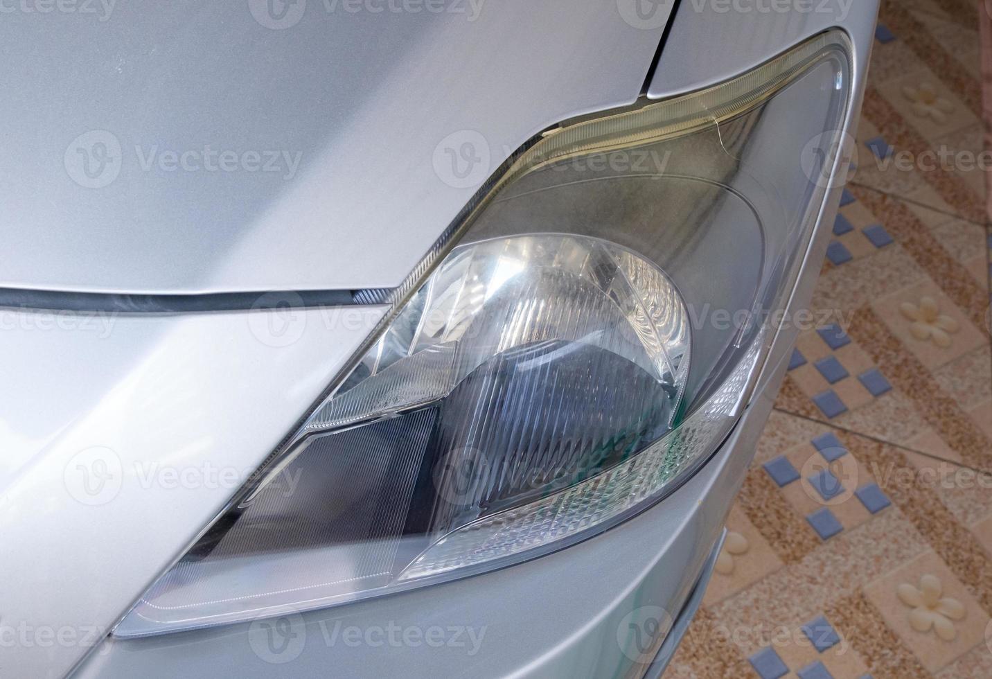The closeup of the unclear headlight on the small sedan car. photo