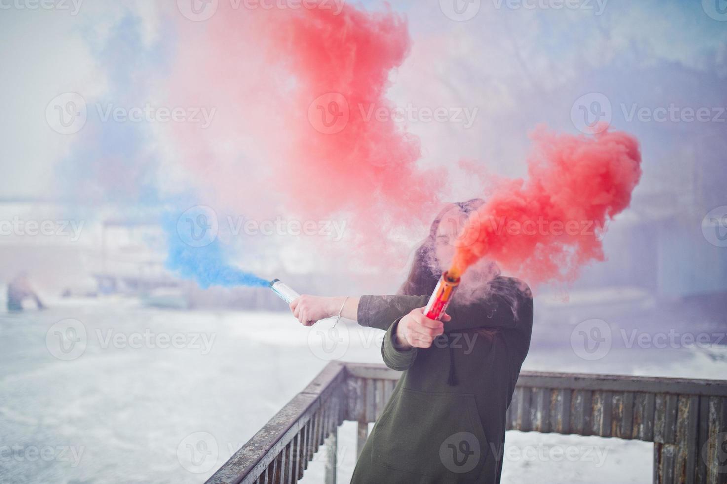 Young girl with blue and red colored smoke bomb in hands. photo