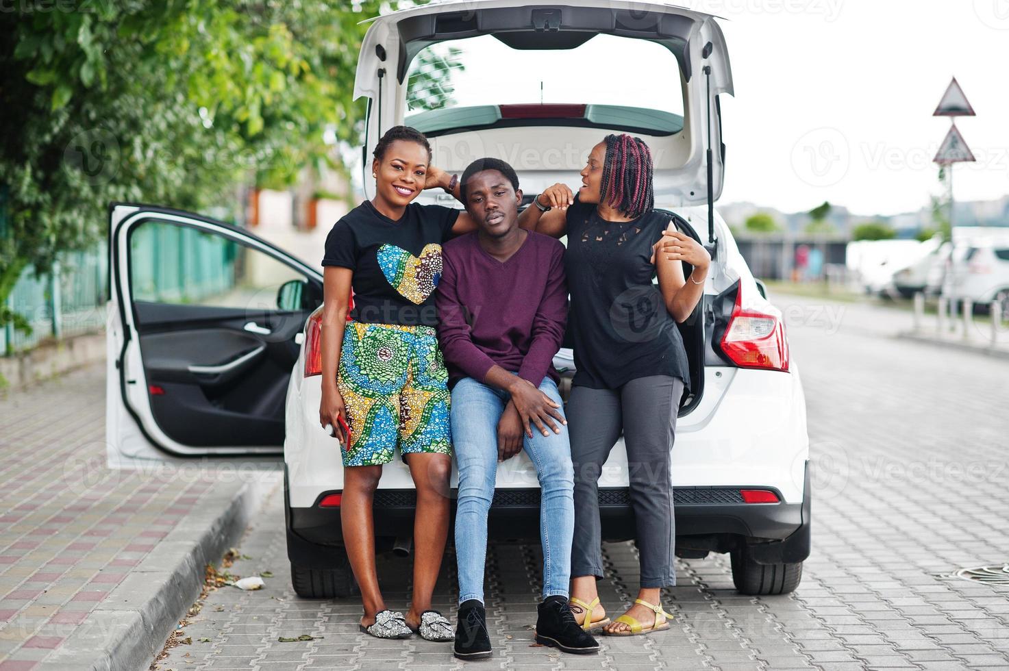 Three african american friends sit in the trunk of the car. photo