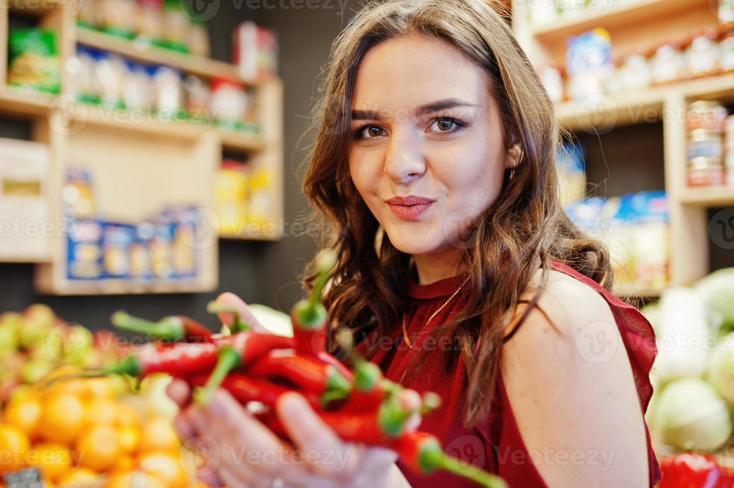 chica de rojo con pimientos picantes en la tienda de frutas. foto