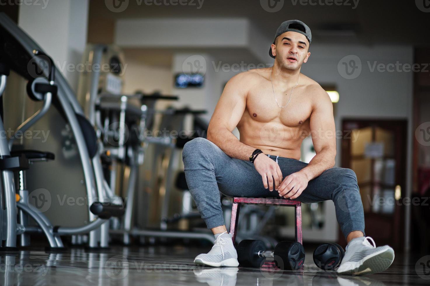 Fit and muscular arabian man doing workouts in gym. photo