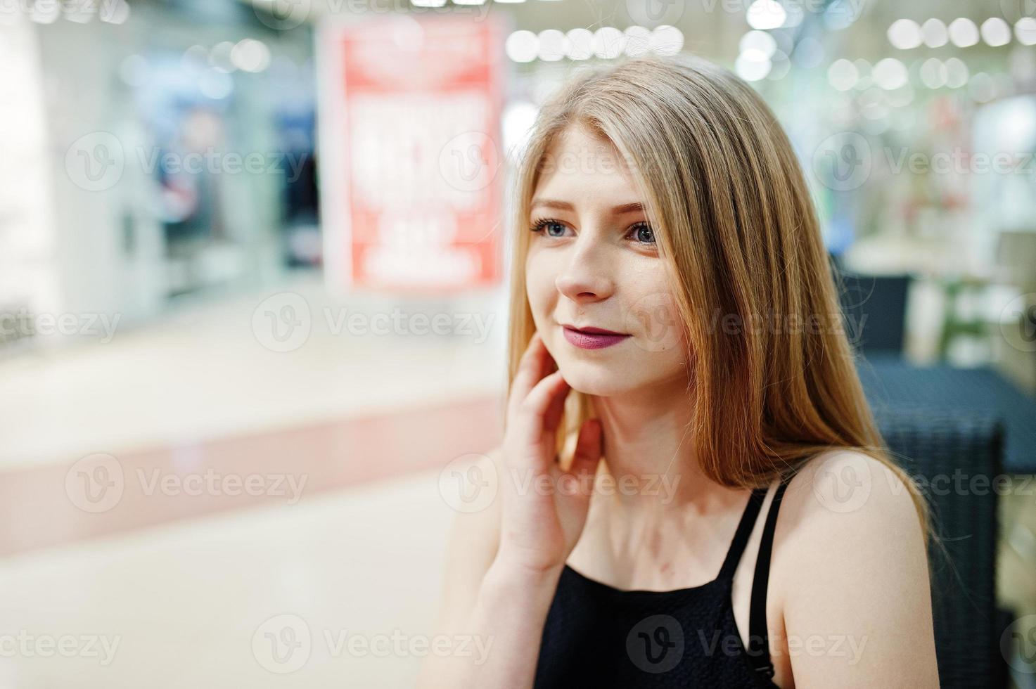 Close up portrait of blonde girl sitting on the mall. photo