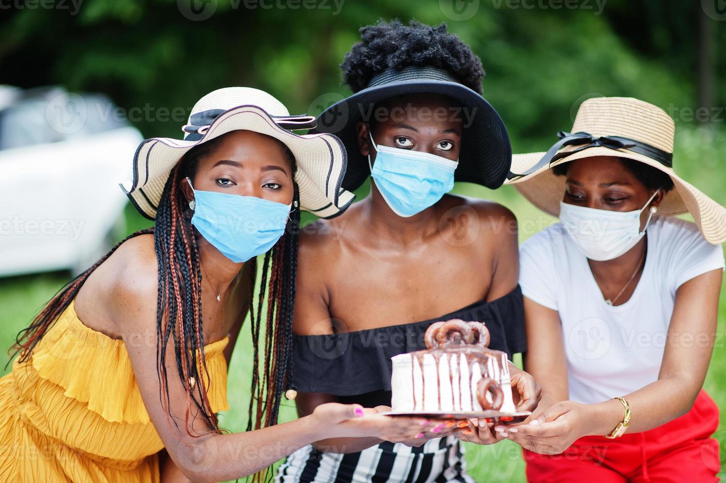 Group of african american girls with facial masks celebrating birthday party outdoor with decor during coronavirus pandemia. photo