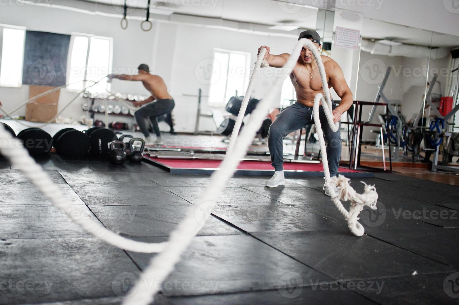 hombre árabe en forma y musculoso trabajando con cuerdas pesadas en el gimnasio. foto