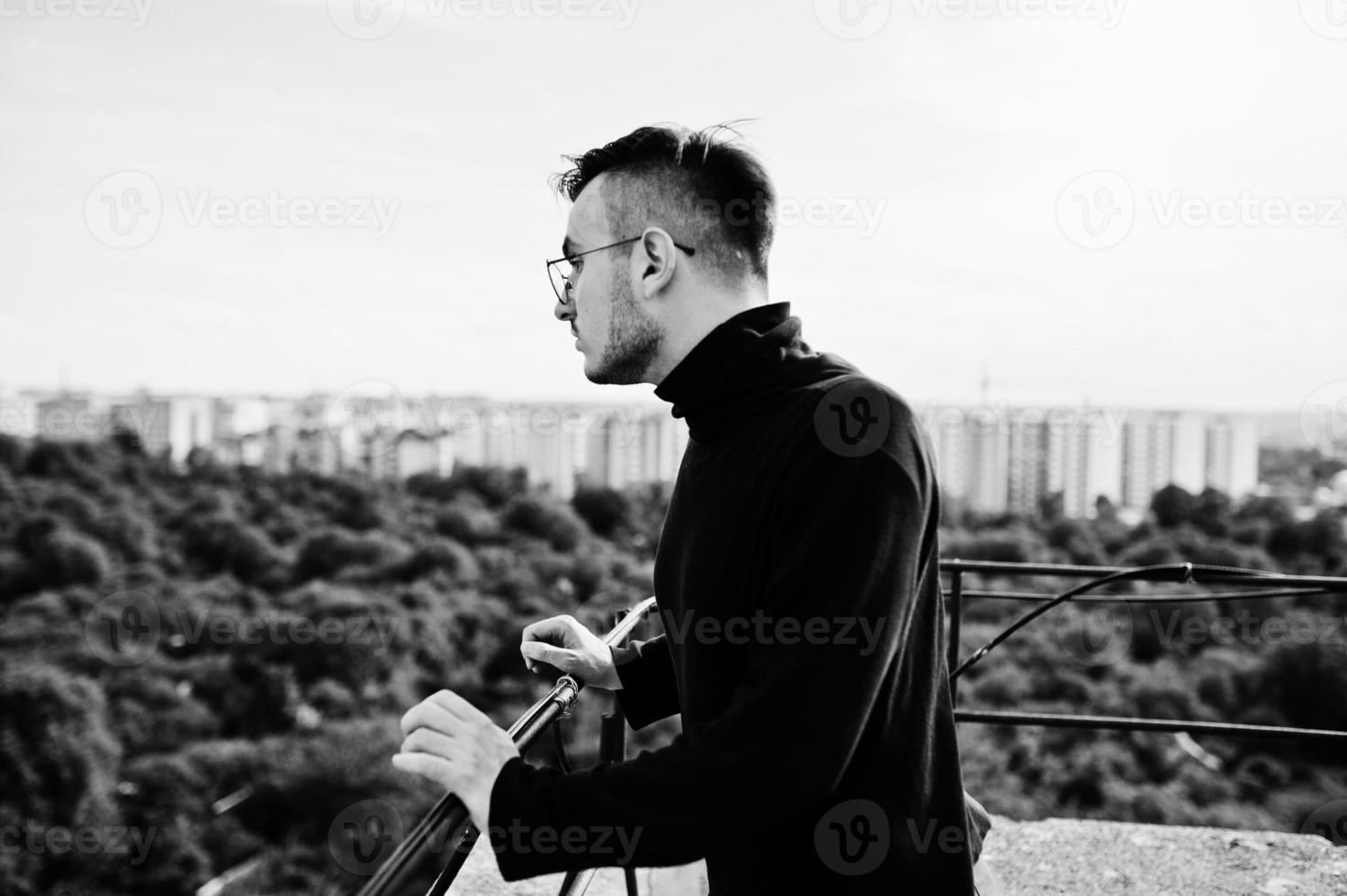 hombre macho con estilo soñador en golf negro y gafas posadas en el techo. foto