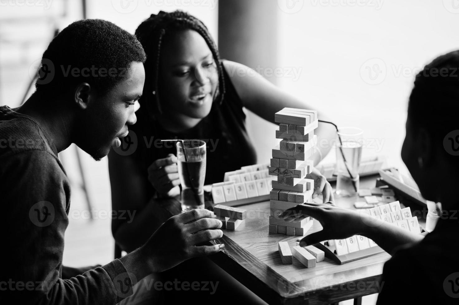 Group of three african american friends play table games. photo