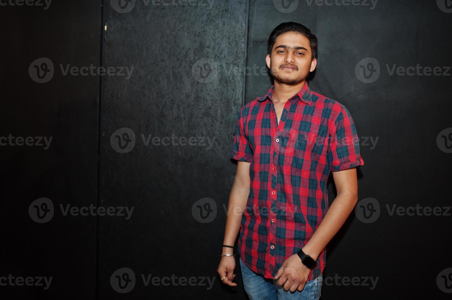 Asian man in checkered shirt against dark background. photo