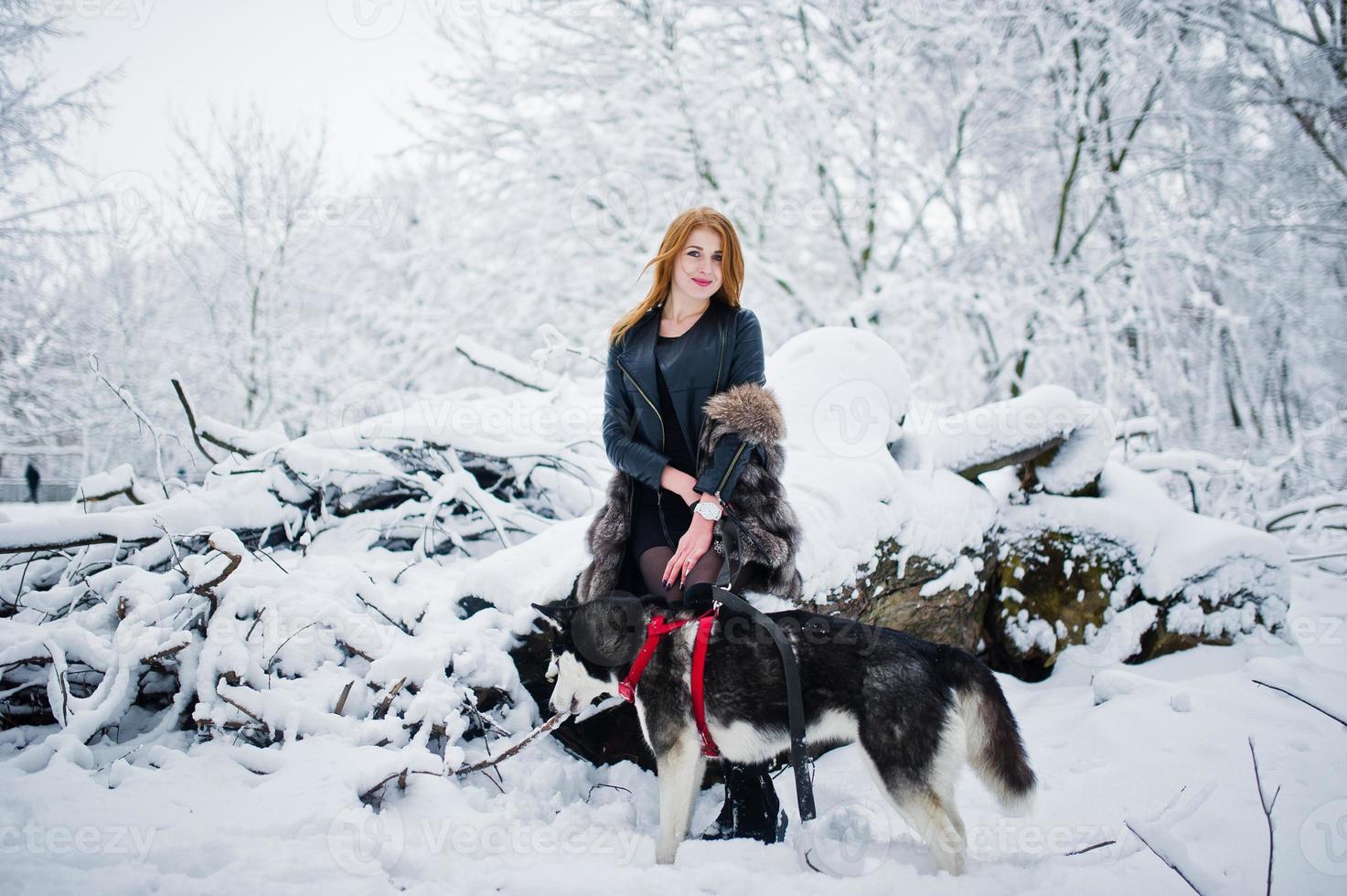 Red haired girl walking at park with husky dog on winter day. photo