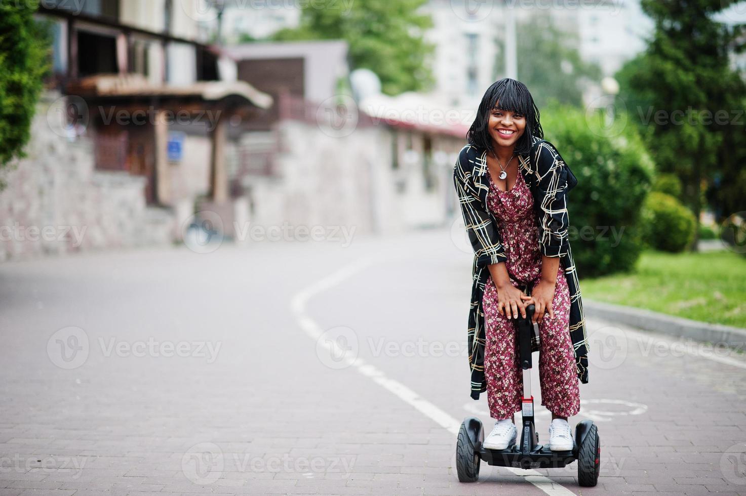 Beautiful african american woman using segway or hoverboard. Black girl on dual wheel self balancing electrical scooter. photo
