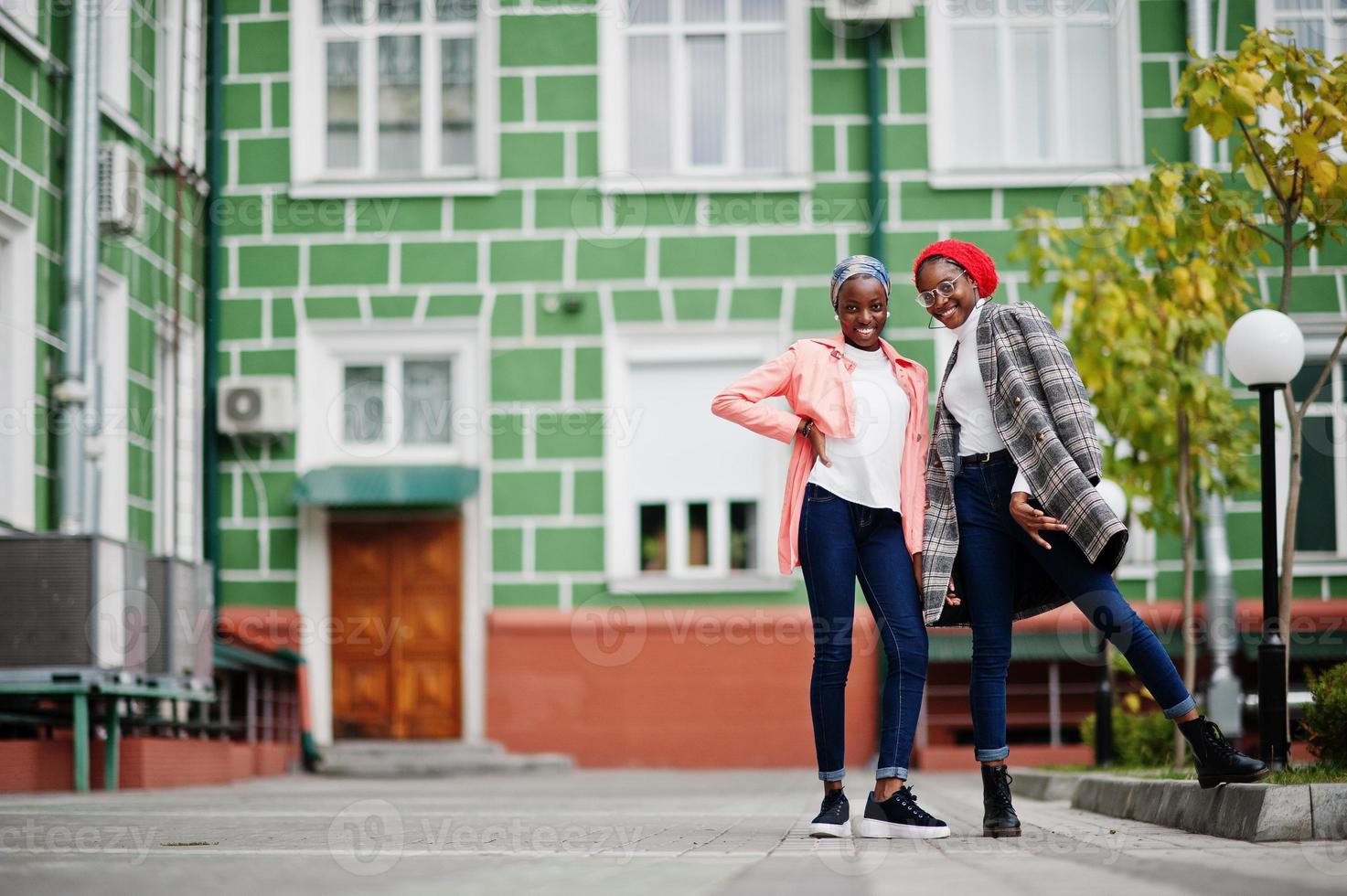 Two young modern fashionable, attractive, tall and slim african muslim womans in hijab or turban head scarf and coat posed. photo