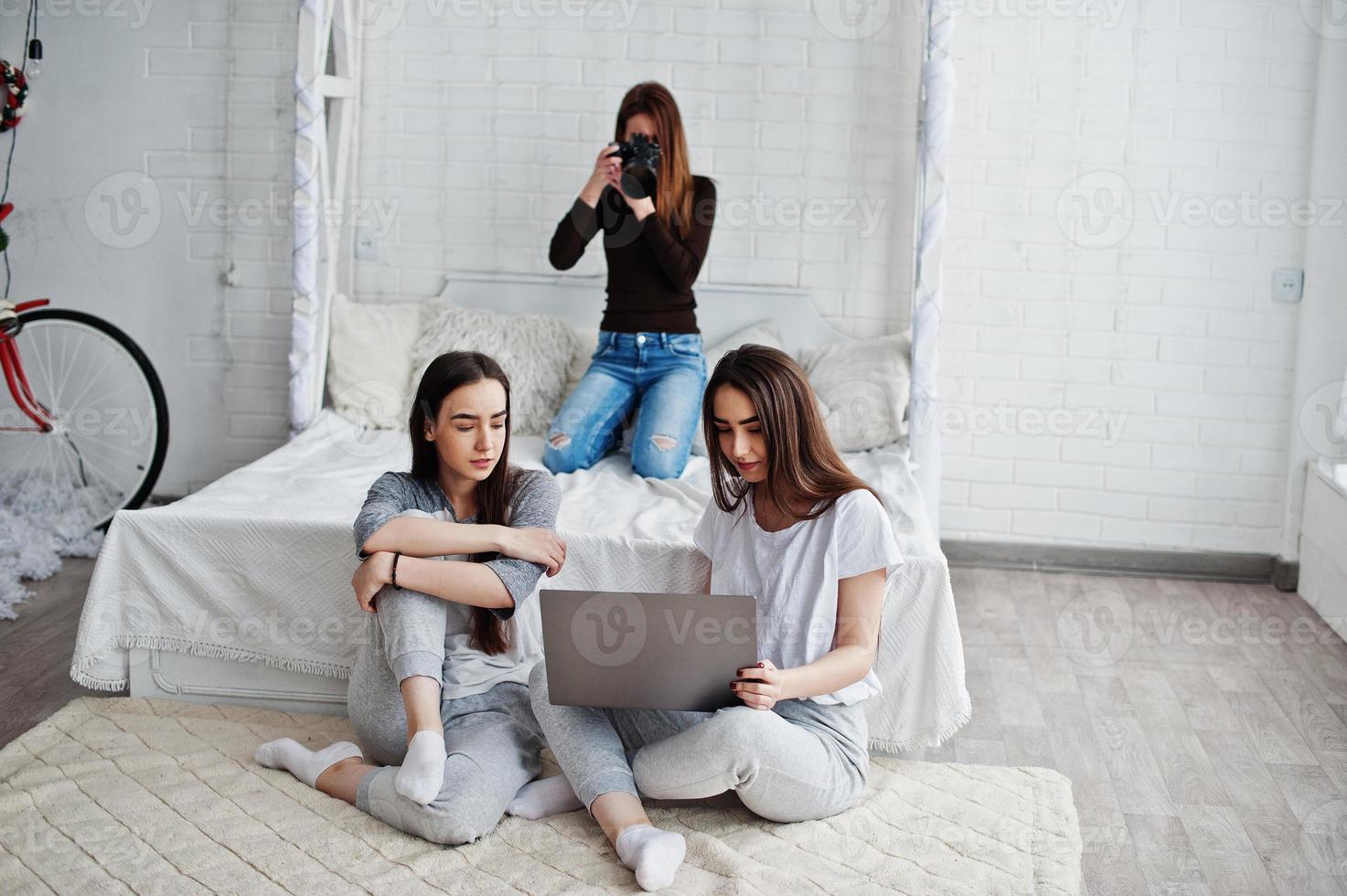 Young girl photographer shooting on studio two twins girls who are watching laptop. Professional photographer on work. photo