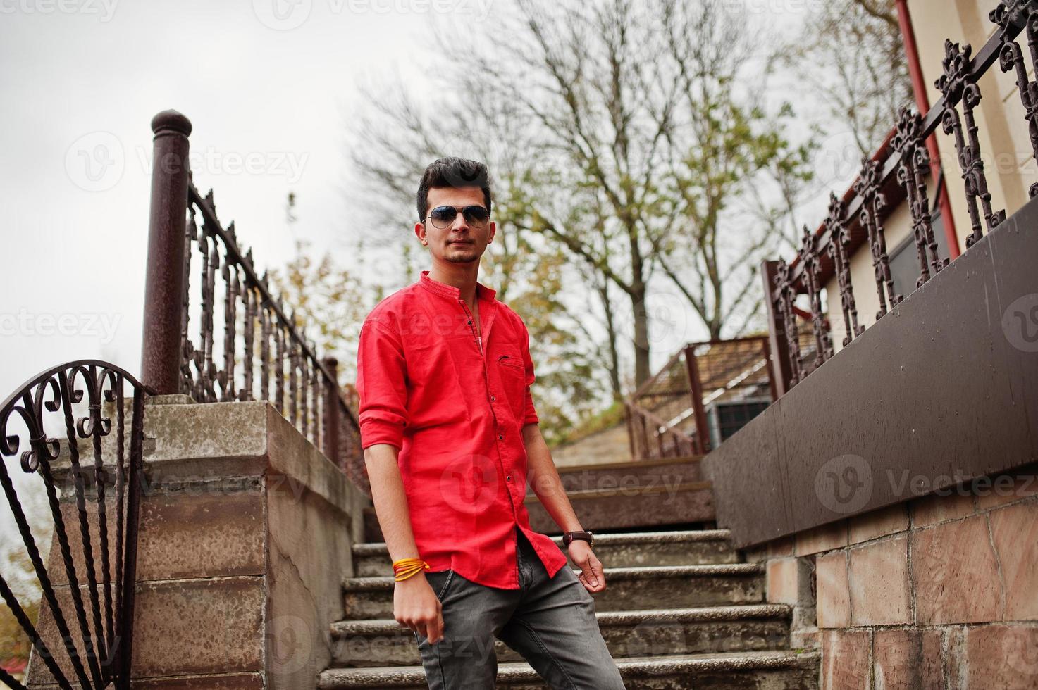 Indian man at red shirt and sunglasses posed outdoor. photo