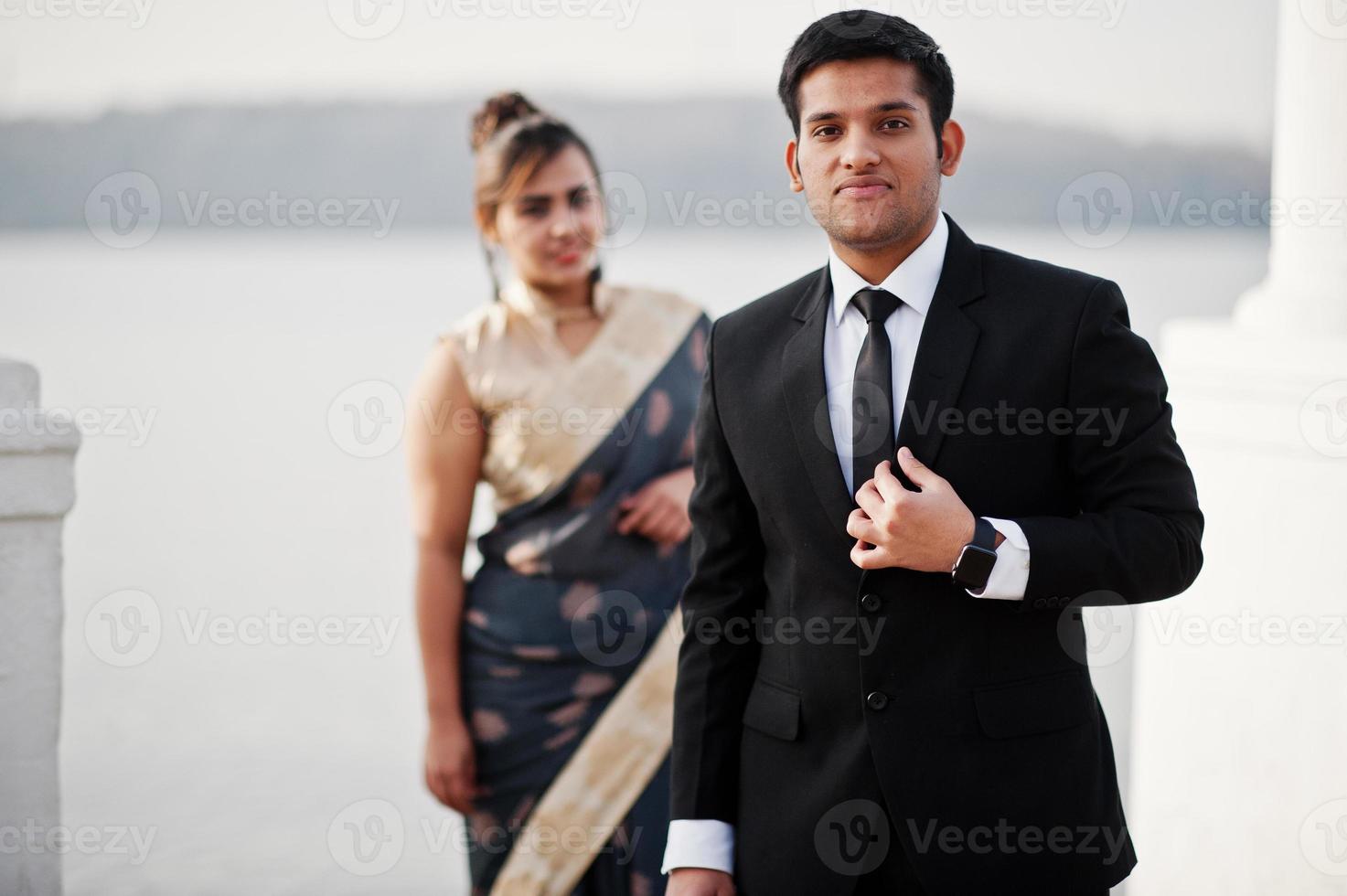 elegante y de moda amigos indios pareja de mujer en sari y hombre en traje posaron en la orilla del puerto deportivo. foto