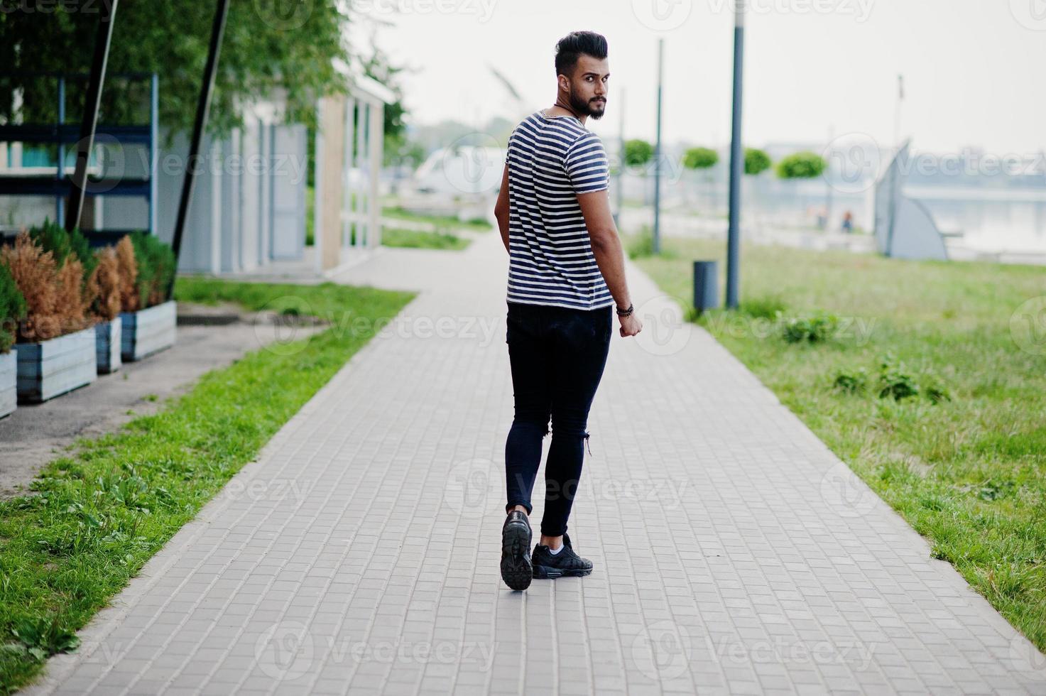 Handsome tall arabian beard man model at stripped shirt posed outdoor. Fashionable arab guy. photo