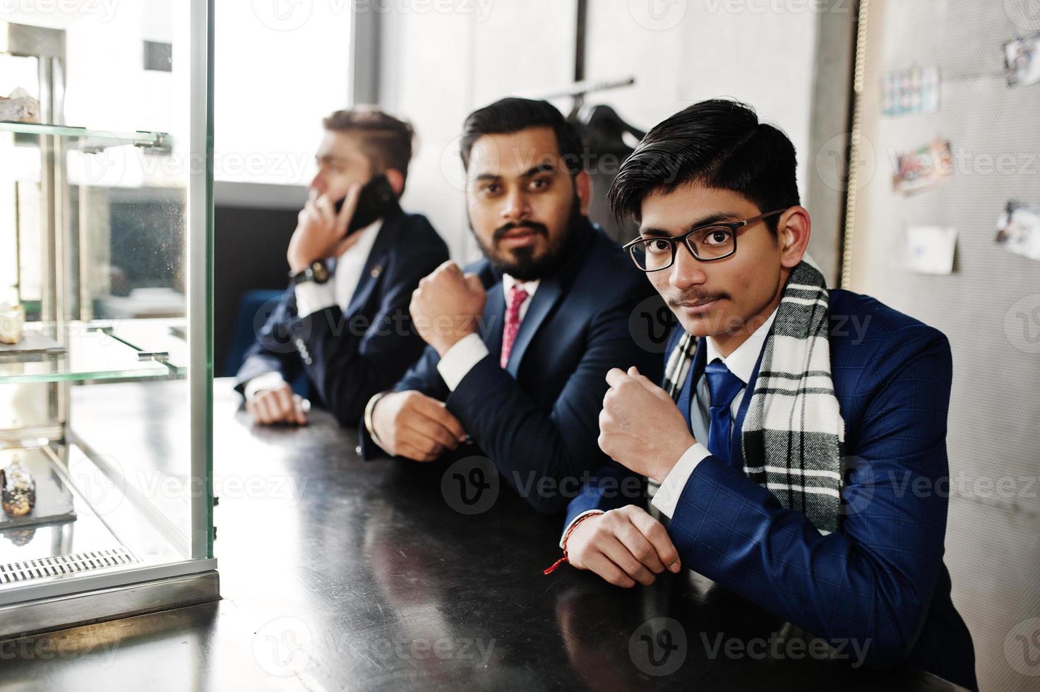 Group of three indian businessman in suits sitting on cafe. photo