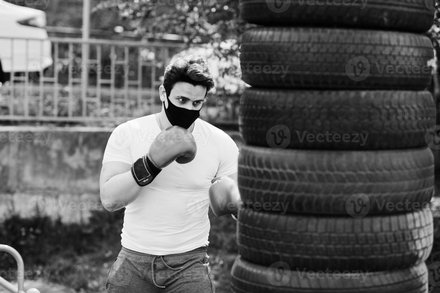 Portrait sports arabian boxer man in black medical face mask boxing outdoor during coronavirus quarantine. photo