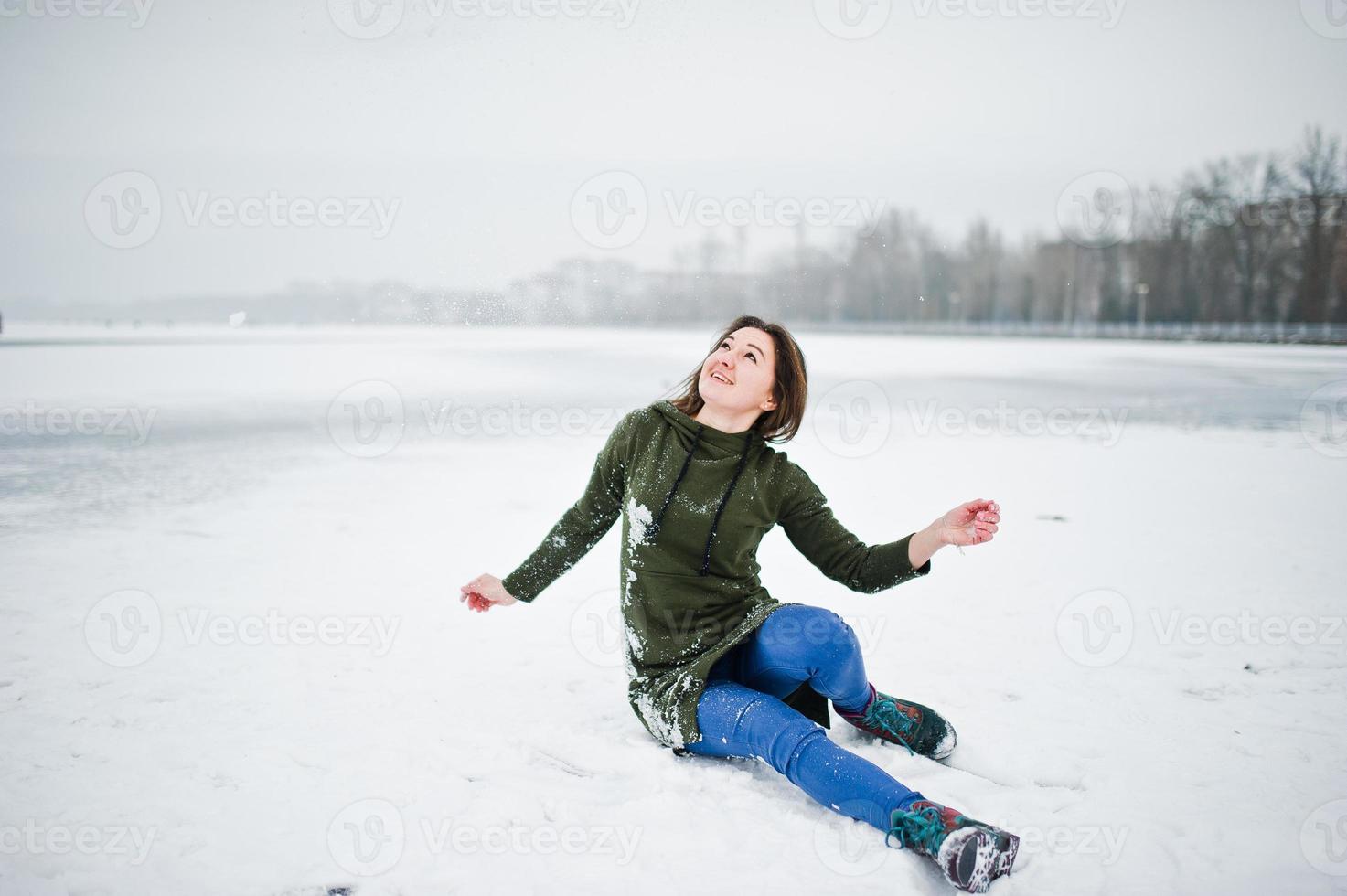 Funny girl wear on long green sweatshirt and jeans, at frozen lake in winter day. photo