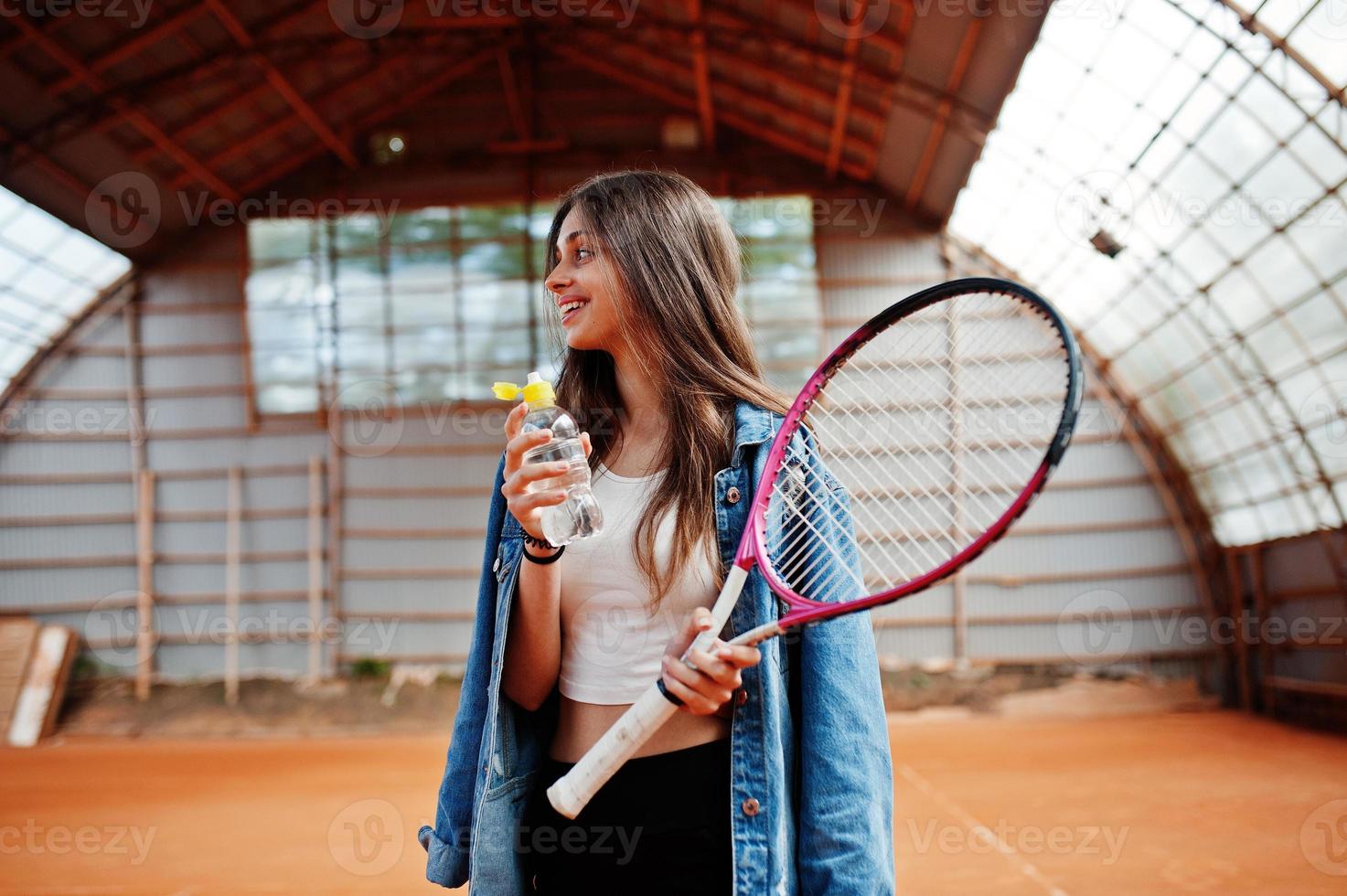 Young sporty girl player with tennis racket on tennis court. photo