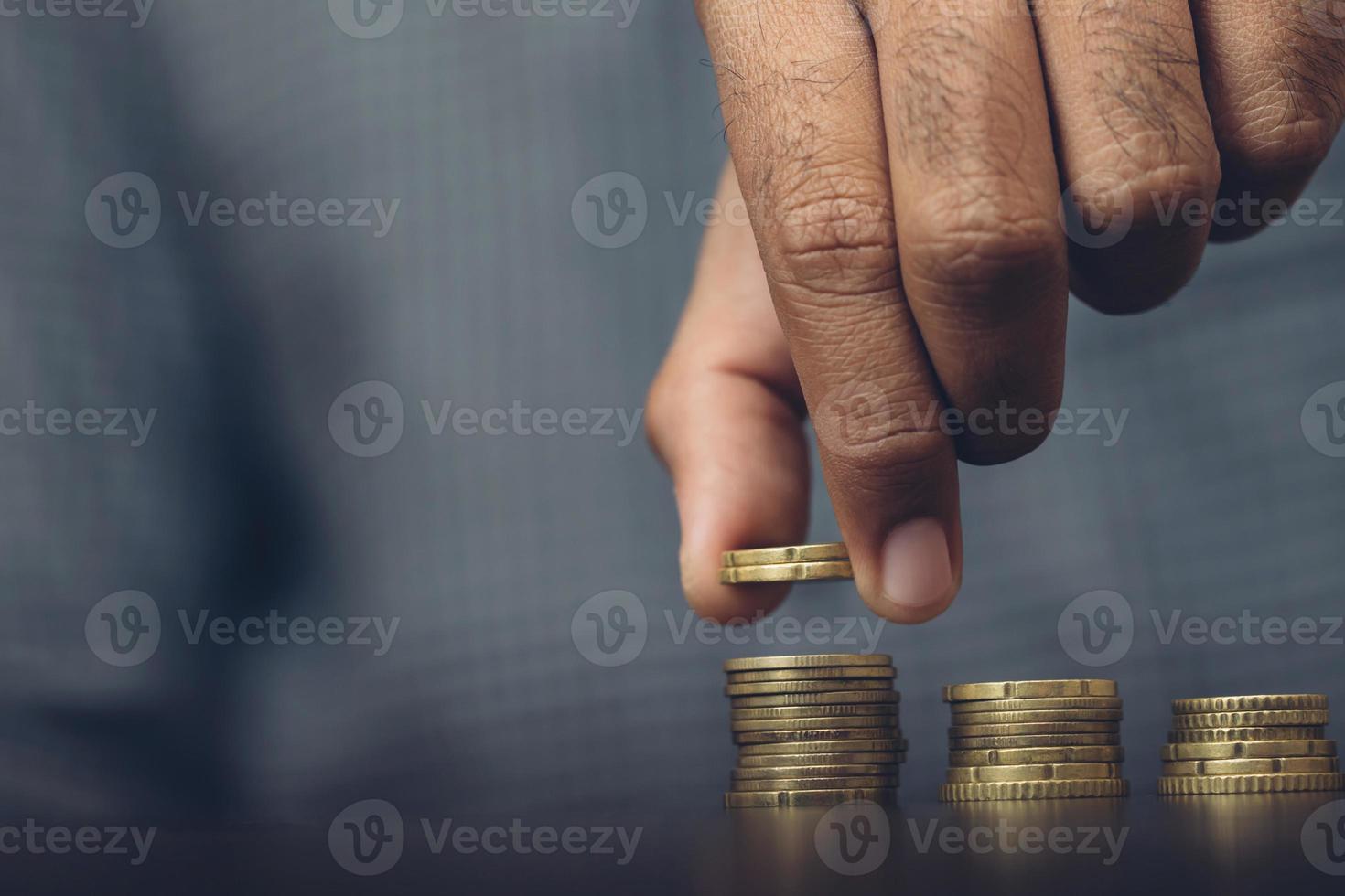 Saving money. businessman hand putting stack coins to show concept of growing savings money finance business and wealthy. blackamoor people. photo