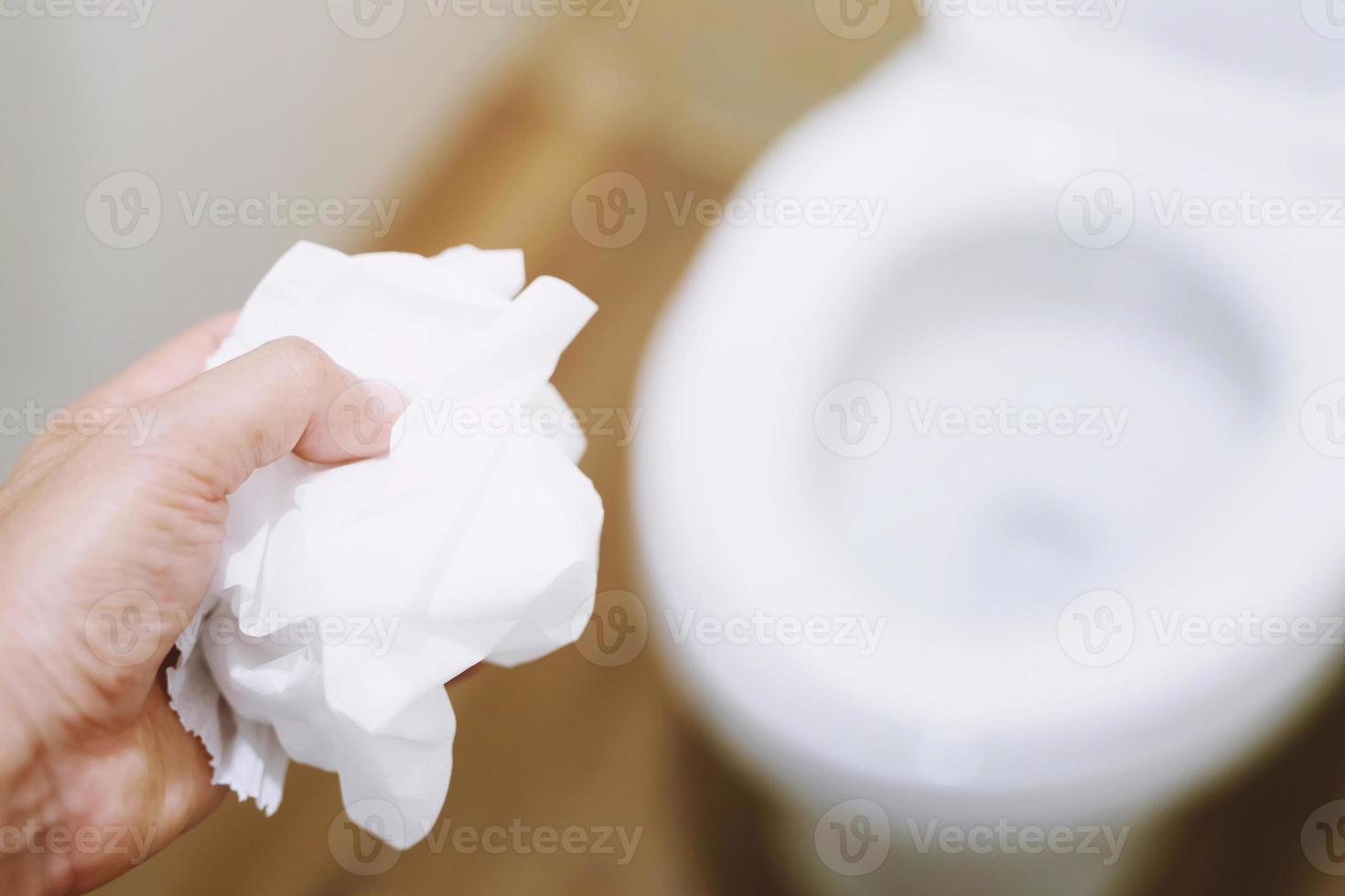 closeup of a young man throwing a wet wipe to the toilet, in a white tiled restroom photo