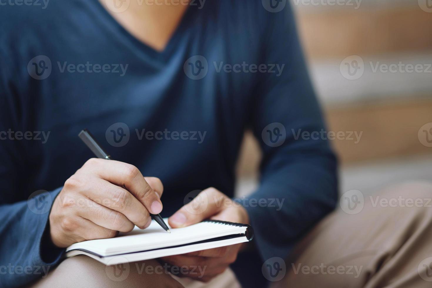 close up hand young man are sitting using pen writing Record Lecture note pad into the book photo