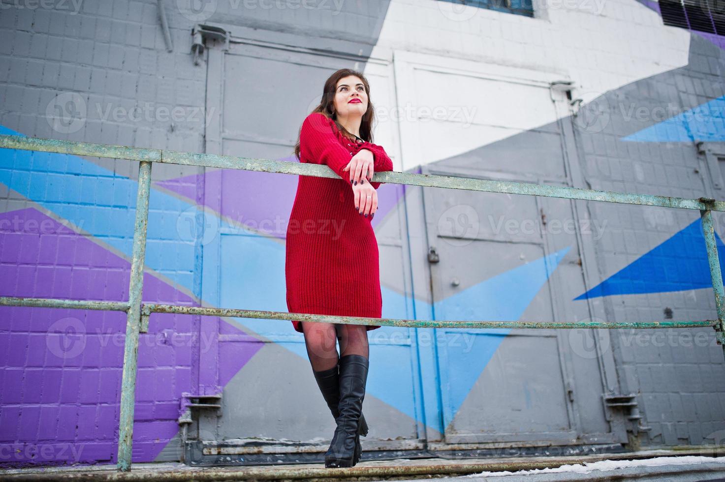 Brunette plus size model at red against colored wall. photo