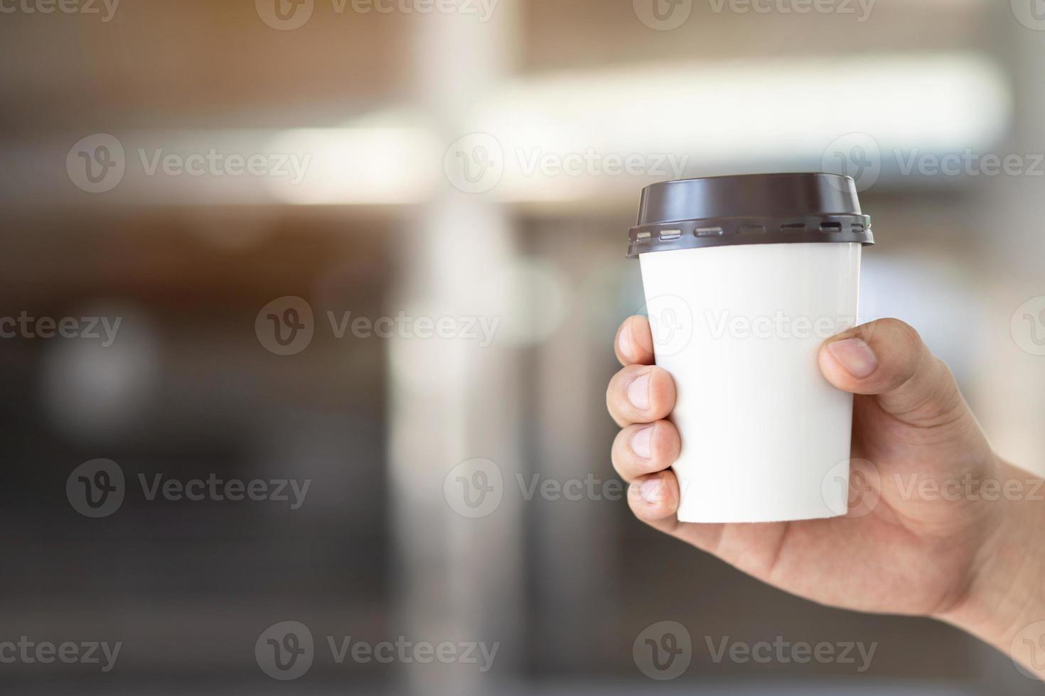 people man hand holding paper cup of take away drinking coffee on natural morning sunlight sitting in public park. space Place for your text or logo. photo