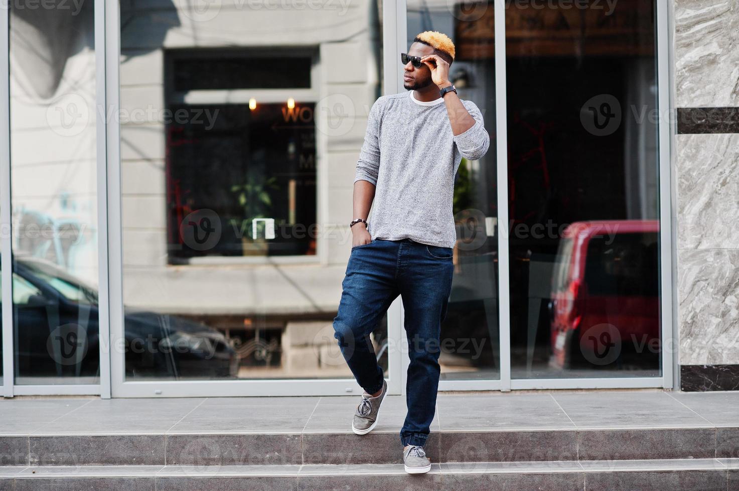 Stylish african american boy on gray sweater and black sunglasses posed at street. Fashionable black guy. photo