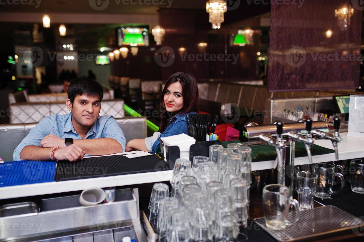 Stylish asian couple wear on jeans sitting on chair at bar in club. photo