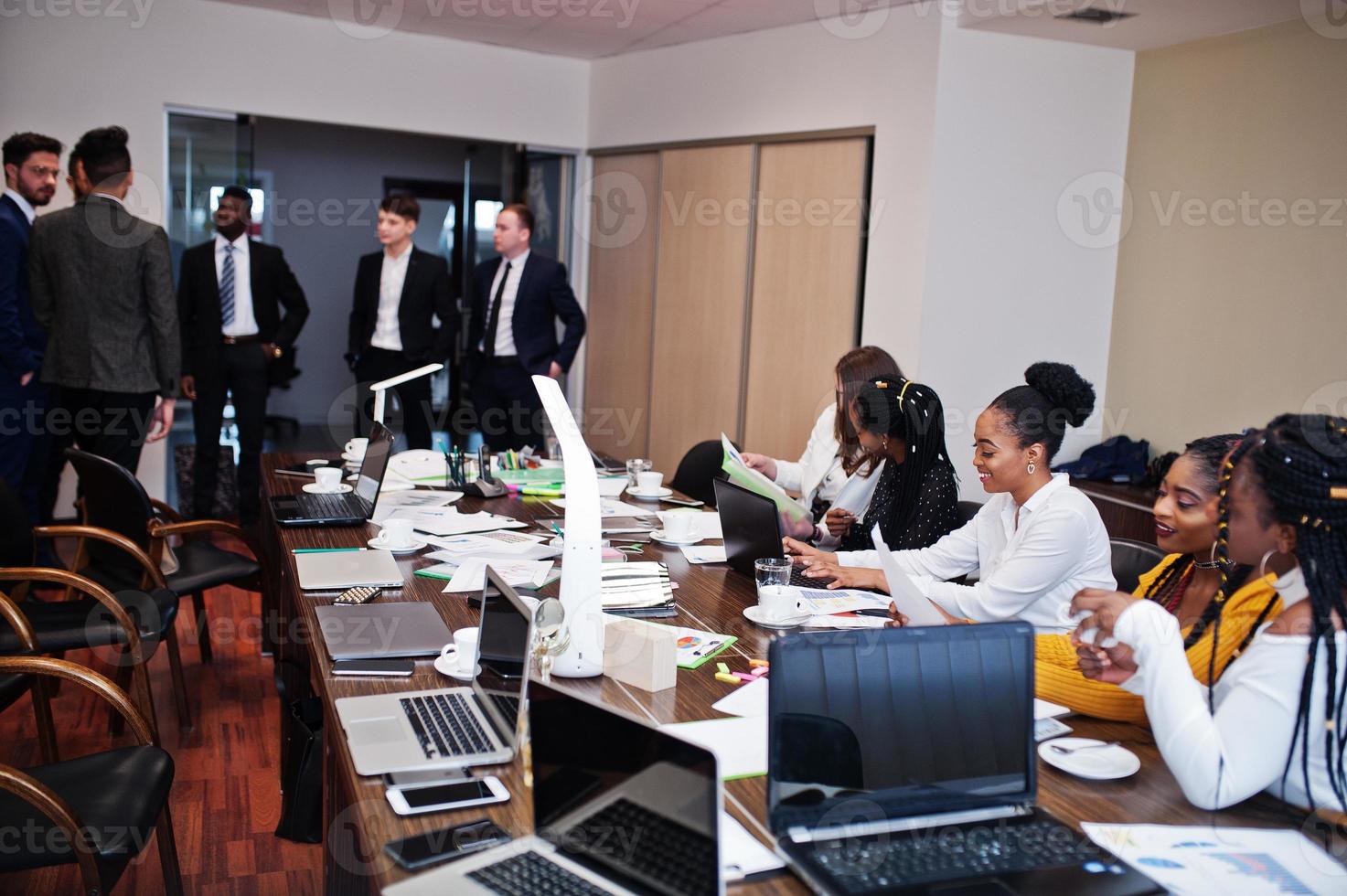 equipo de negocios multirracial que aborda la reunión alrededor de la mesa de juntas. foto