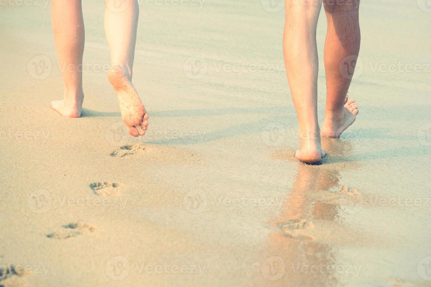 primer plano de una dama mujer y hombre pareja amante pies descalzos caminando y huella en mojado en la playa romántica luna de miel. vacaciones en la playa del océano, pie en la arena del mar. la sombra del sol golpea la arena. viajar foto