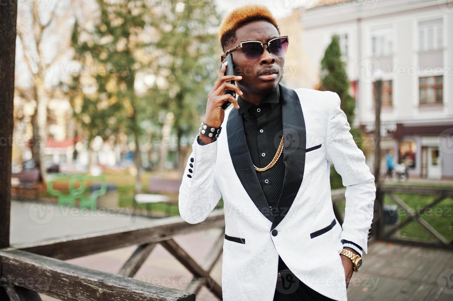 Chic handsome african american man in white suit with mobile phone at hand. photo