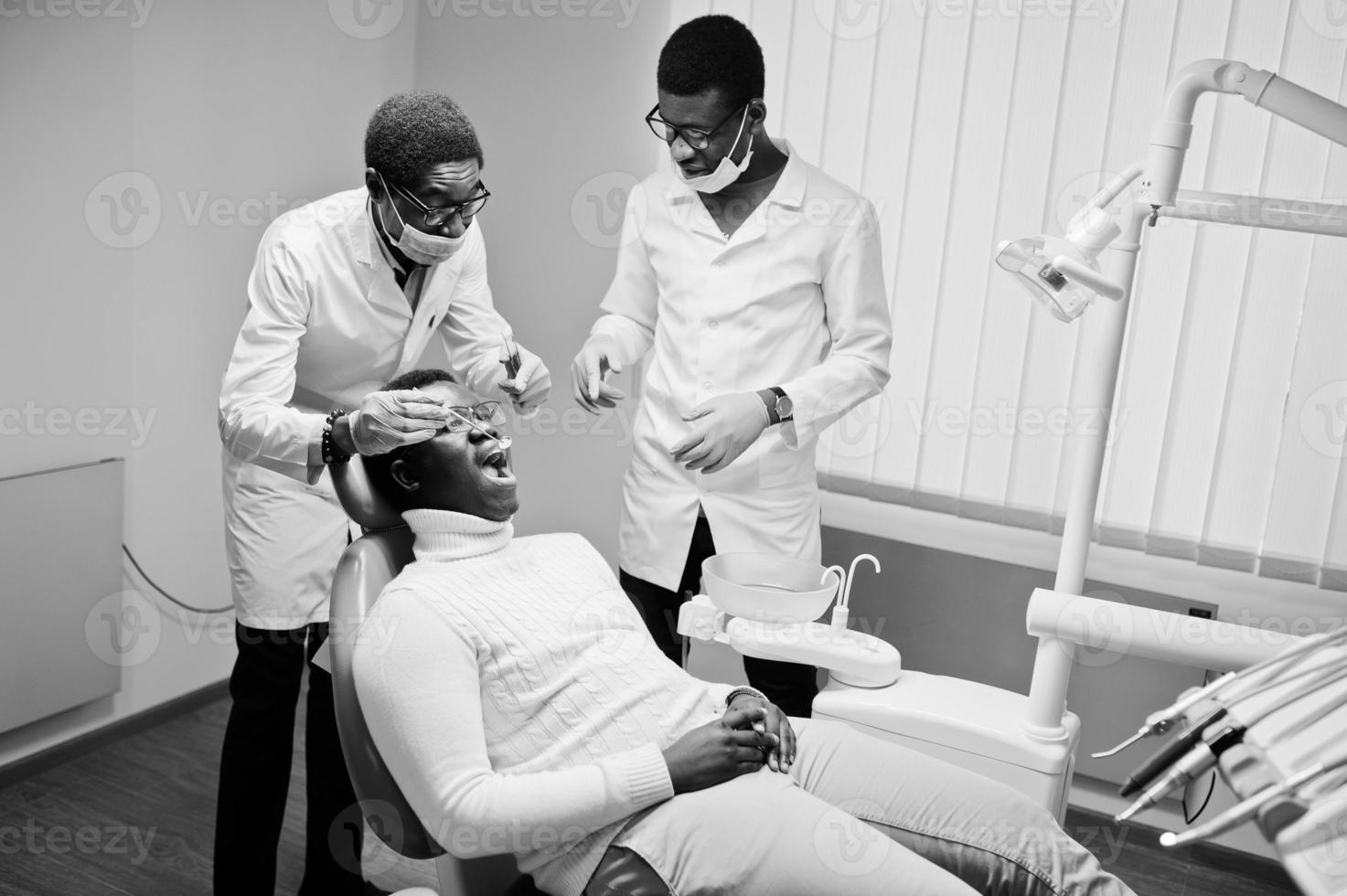 African american man patient in dental chair. Dentist office and doctor practice concept. Professional dentist helping his patient at dentistry medical. photo