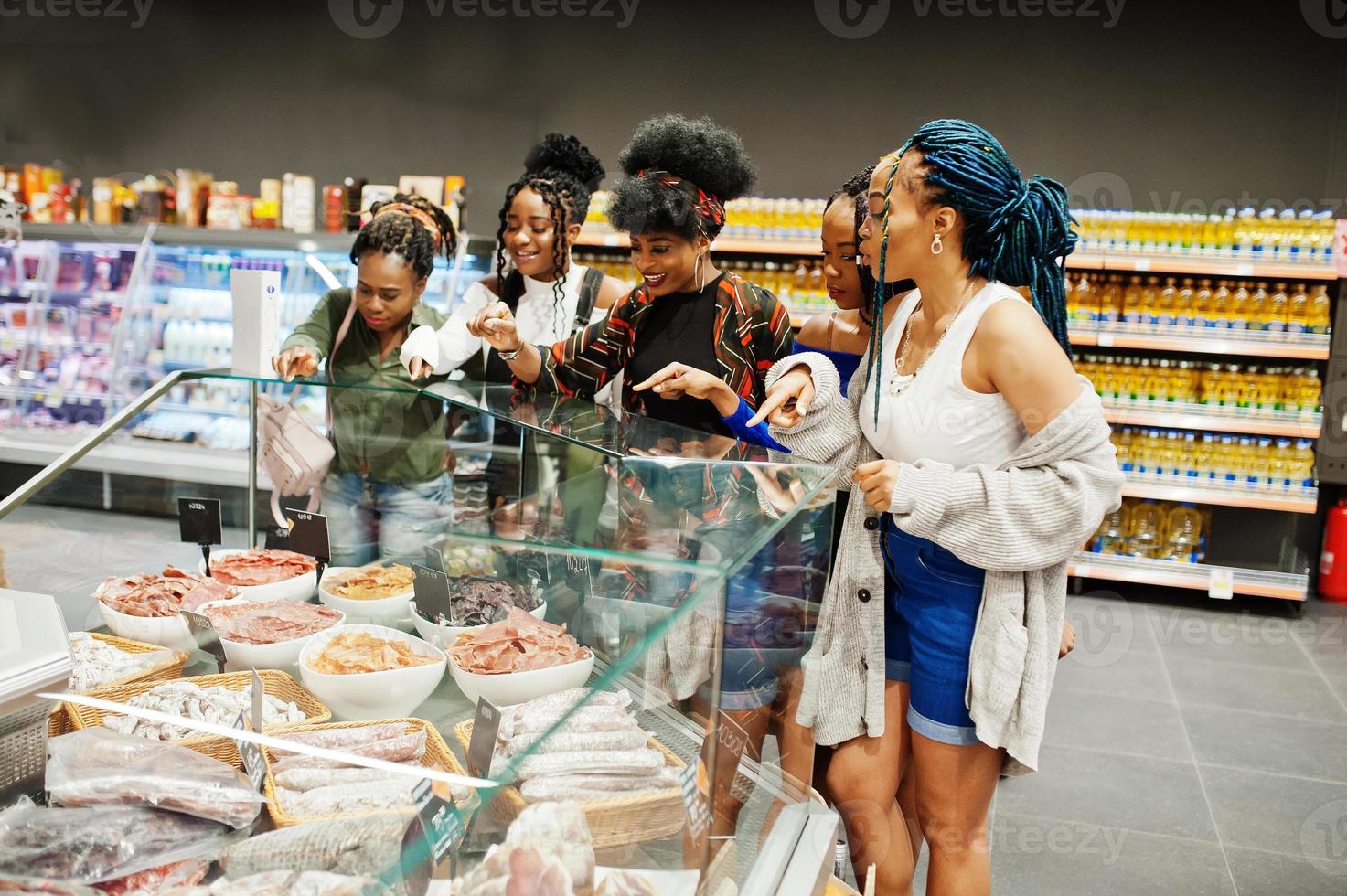 Group of five african womans buying meat dishes in supermarket. photo