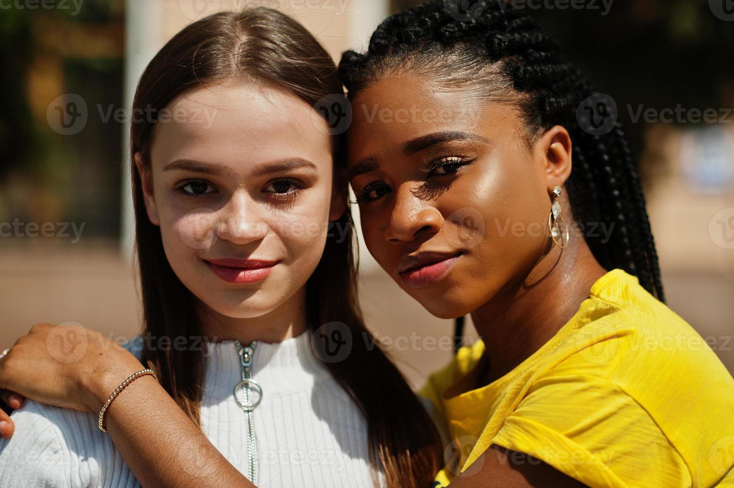 Close up faces of white caucasian girl and black African American together. World unity, racial love, understanding in tolerance and races diversity cooperation. photo