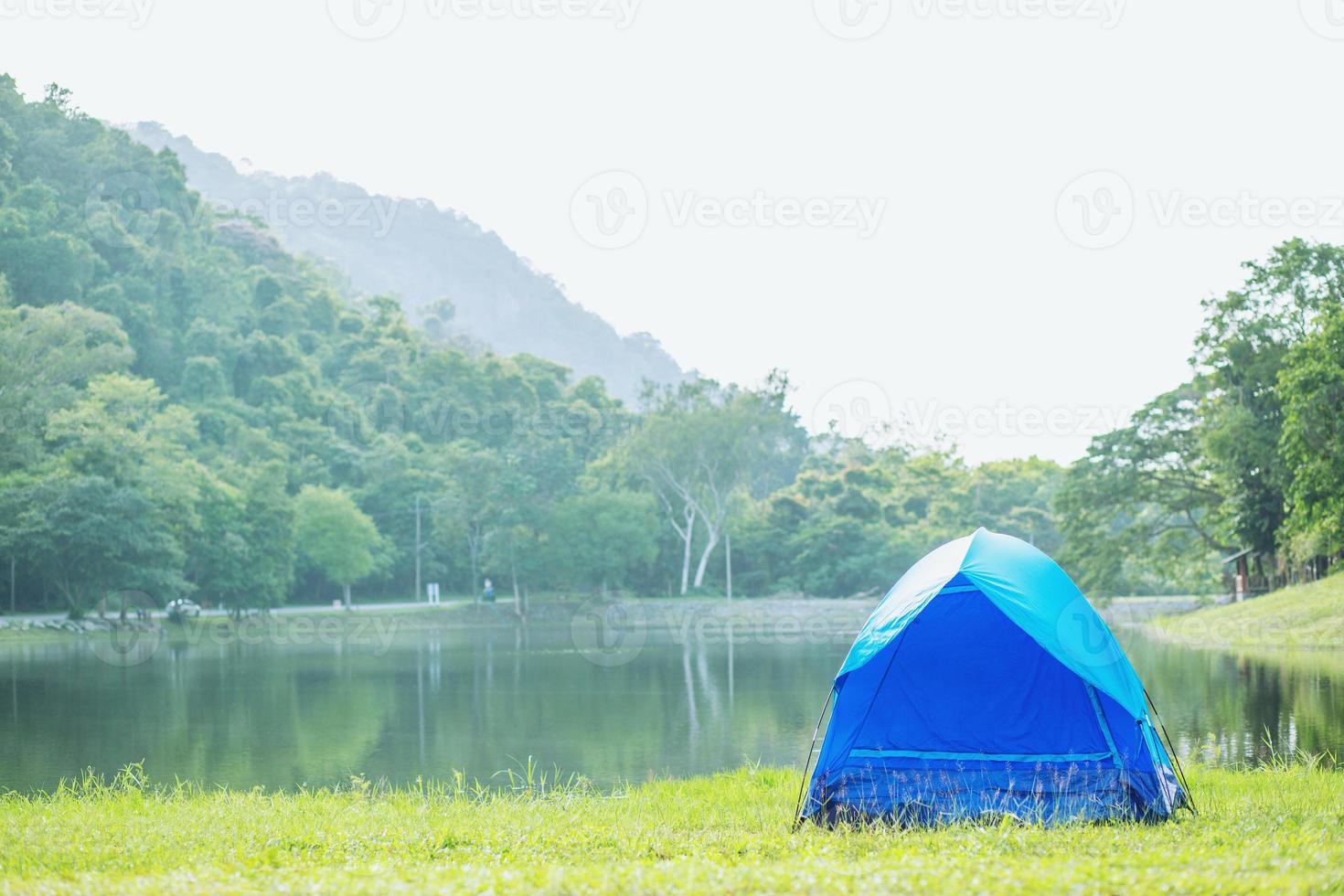 Camping blue tent in forest near lake river in the morning atmosphere refreshing. concept travel. photo