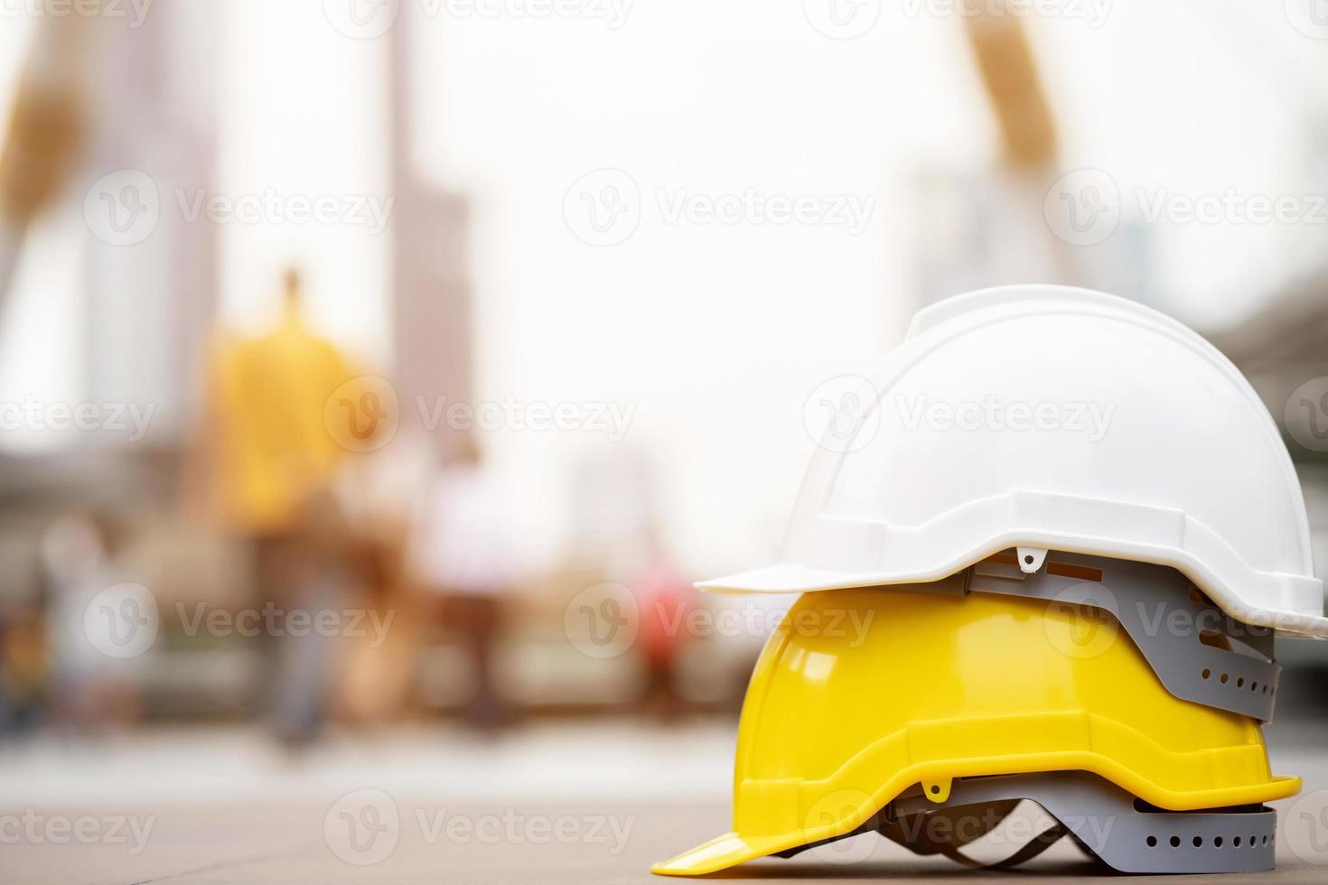 white, yellow hard safety helmet hat for safety project of workman as engineer or worker, on concrete floor on city photo