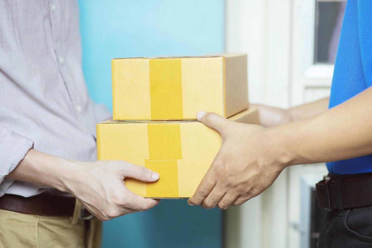 parcel delivery man of a package through a service. and close up hand customer accepting a delivery of boxes from delivery man. photo