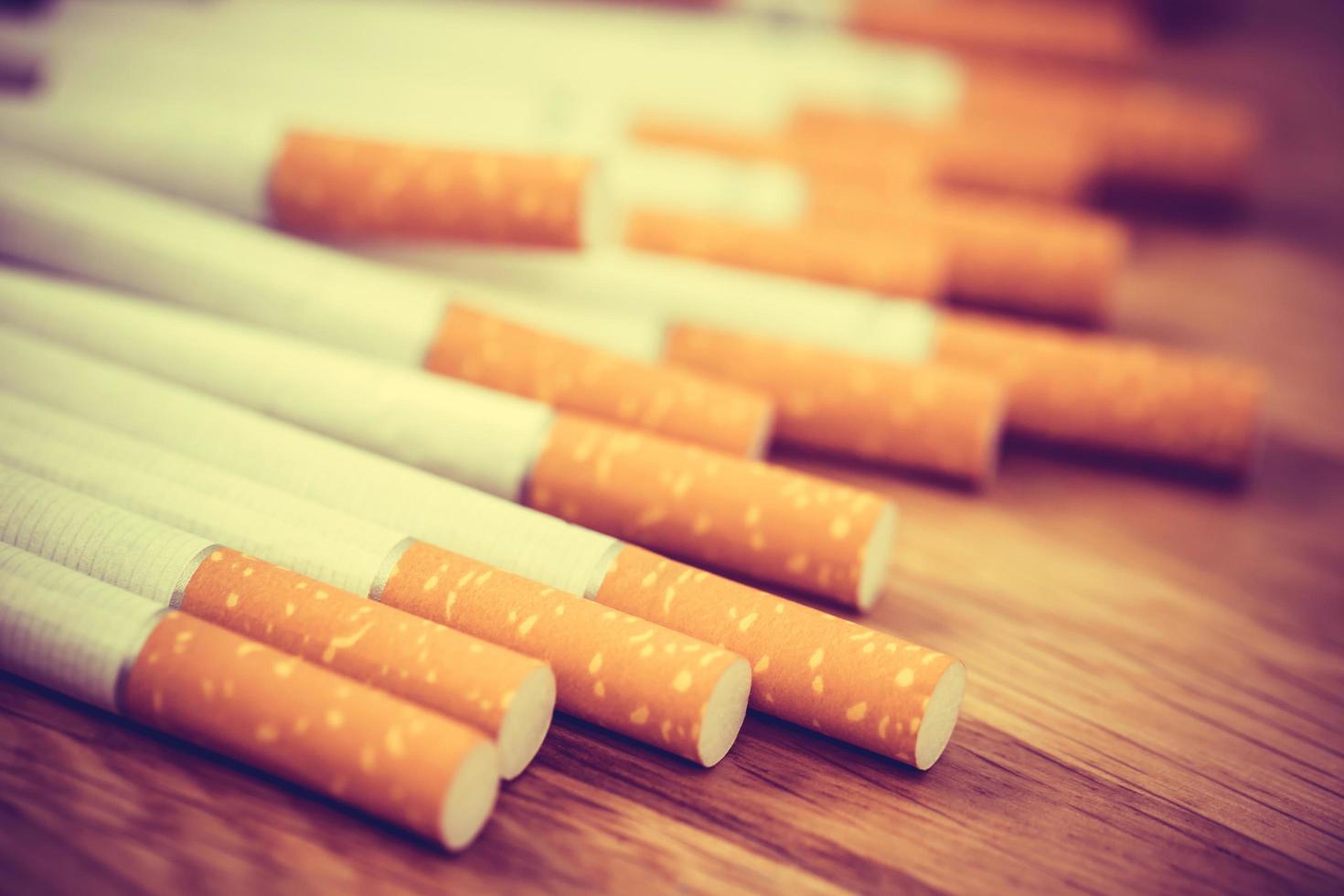 imagen de varios cigarrillos fabricados comercialmente. pila de cigarrillos en madera. o concepto de campaña para no fumadores, tabaco. filtro vintage retro. foto