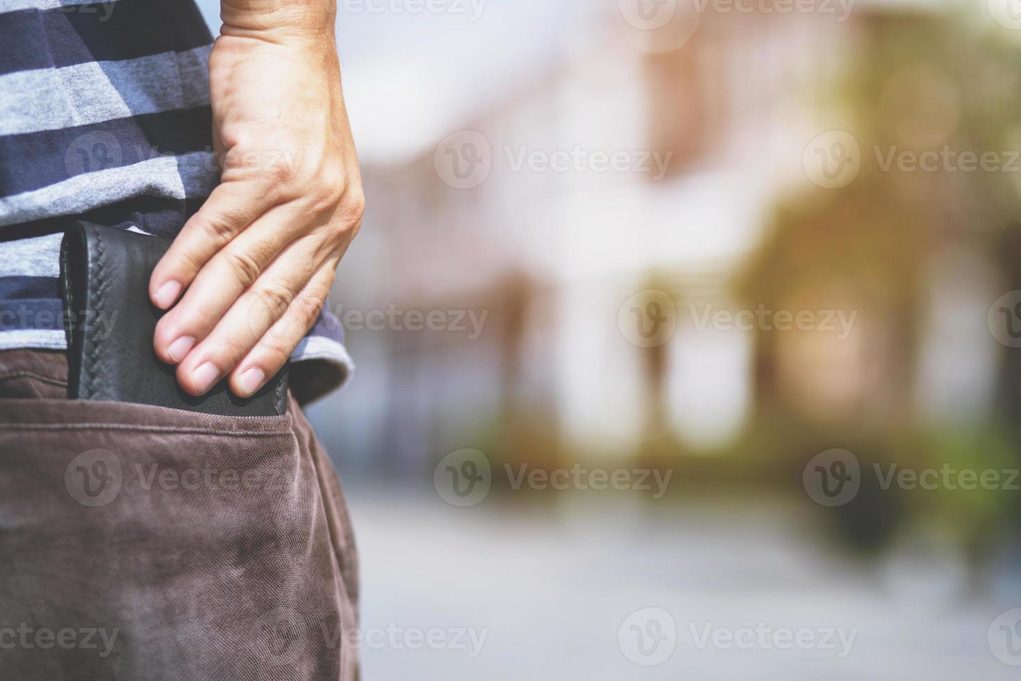 hombre confiado posando en caja fuerte manteniendo su billetera en el bolsillo trasero de sus pantalones de bolsillo trasero. ahorro dinero finanzas. foto