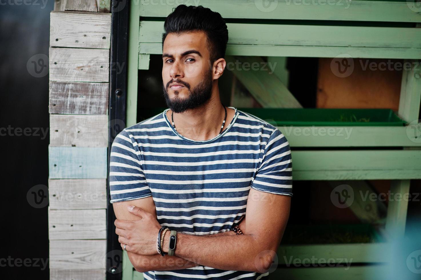 Handsome tall arabian beard man model at stripped shirt posed outdoor. Fashionable arab guy. photo