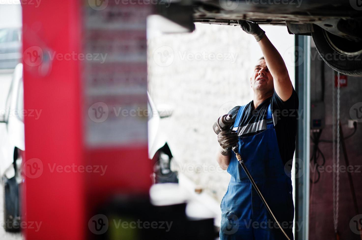 Car repair and maintenance theme. Mechanic in uniform working in auto service. photo