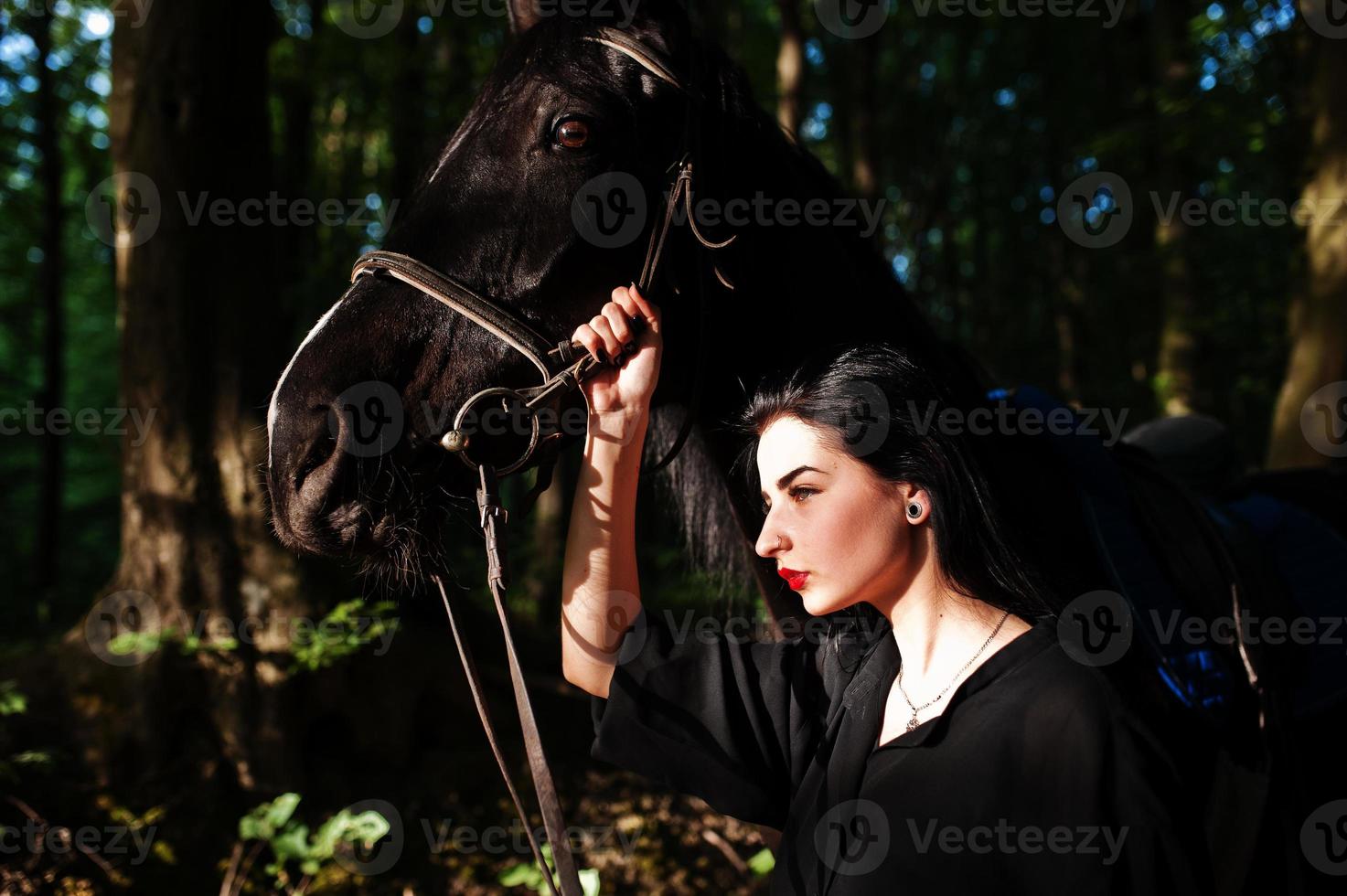Mystical girl wear in black with horse in wood. photo